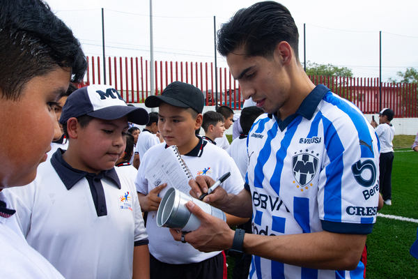Jugador de Rayados firmando un vaso para uno de los niños beneficiados con la cancha