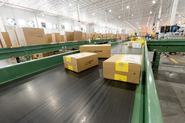 Imagen de un de los centros de distribución de mercado libre, con unas cajas en la banda de distribución