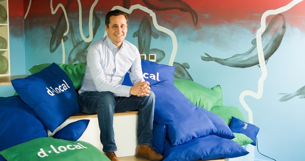 Retrato de Pedro Arnt codirector de dLocal sentado entre cojines de colores brandeados con el nombre de la empresa