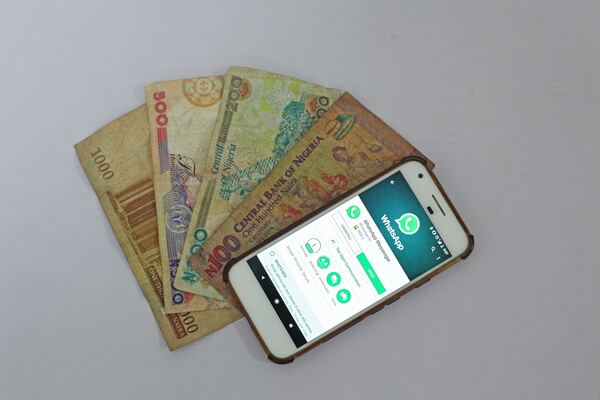 Un celular con whatsapp en la pantalla junto a un abanico de billetes