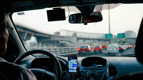 Hombre conduciendo con google maps en la pantalla del celular