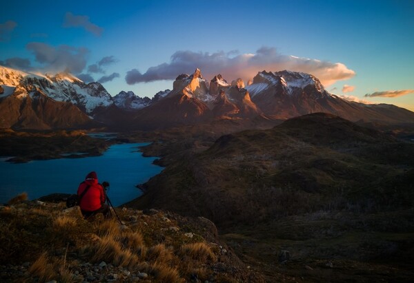 Paisaje montañosos con uno fotógrafo de chamarra roja en primer plano