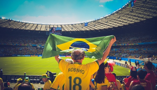 Fanático brasileño sosteniendo una bandera de su país durante un partido de futbol