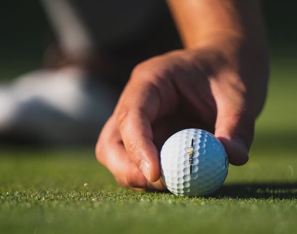 La mano de un golfista en primer plano disponiendo una pelota antes de pegarle