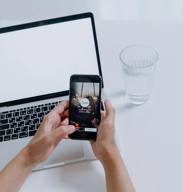 Manos femeninas sosteniendo un celular en el que se lee Canva