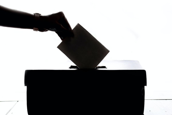 Mano femenina metiendo su voto en una urna