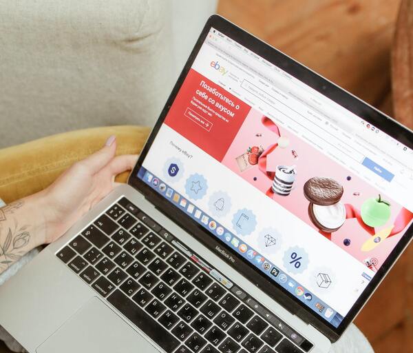 Unas manos femeninas sosteniendo una laptop con un sitio de compras en línea en la pantalla