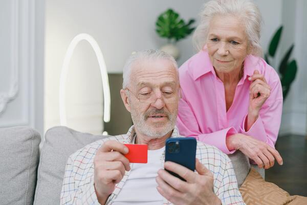 Abuelos con un celular y una tarjeta de crédito en la mano