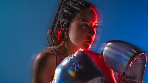 Mujer joven con guantes de box, en posición de ataque, iluminada con luz roja