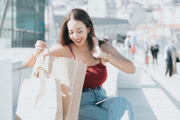 Mujer joven con bolsas de compras en las manos mientras sonríe