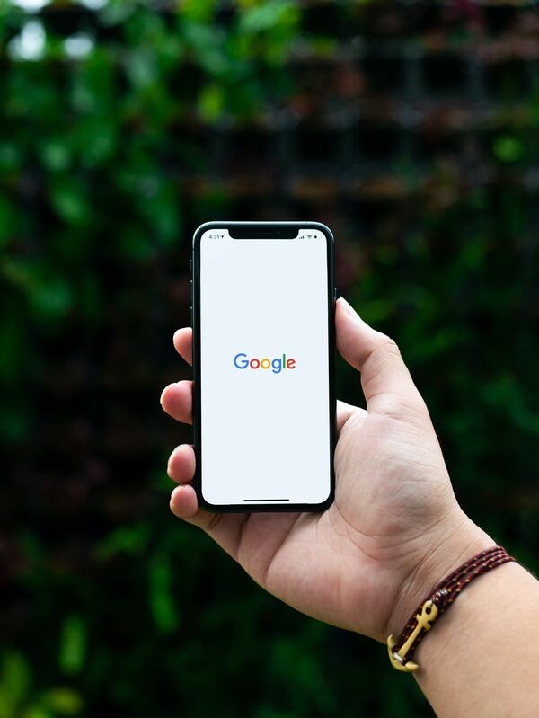 Una mano sosteniendo una celular, mientras en la pantalla se aprecia el buscador de Google