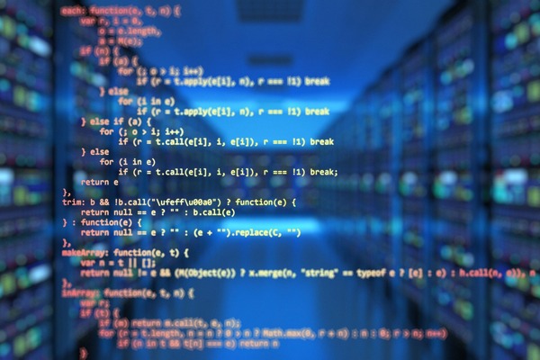 Foto de un data center de fondo, con lenguaje informático en primer plano