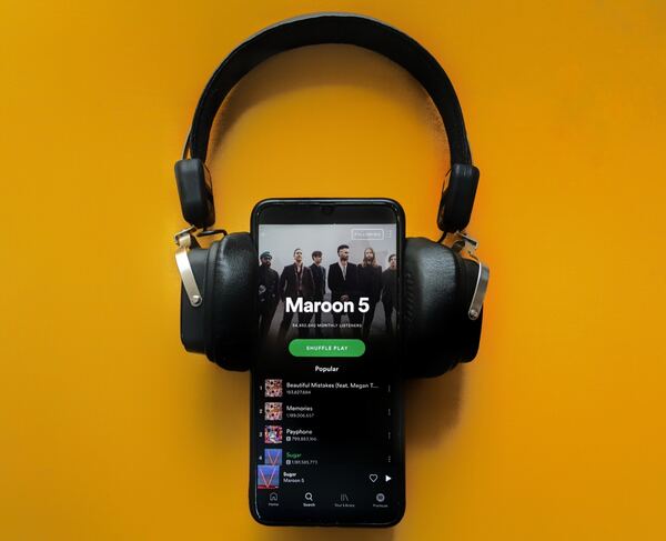 Foto de un celular "escuchando" a Maroon 5 con audífonos de diadema