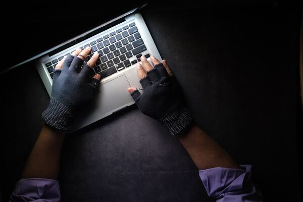 Un par de manos, cubiertas con guates de invierno cortados, sobre una PC